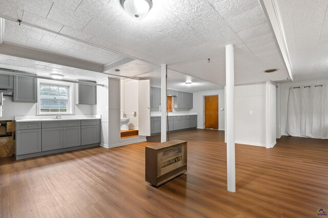 kitchen with a textured ceiling, gray cabinetry, and hardwood / wood-style flooring