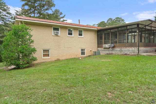 rear view of property with a sunroom, central AC unit, and a yard