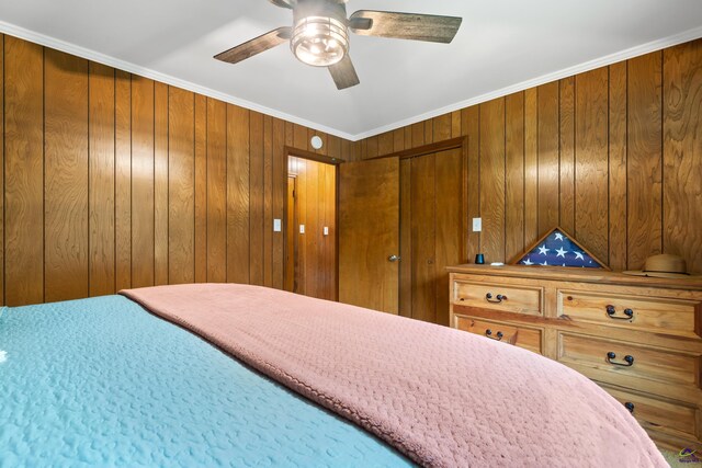 bedroom featuring ornamental molding, wood walls, and ceiling fan