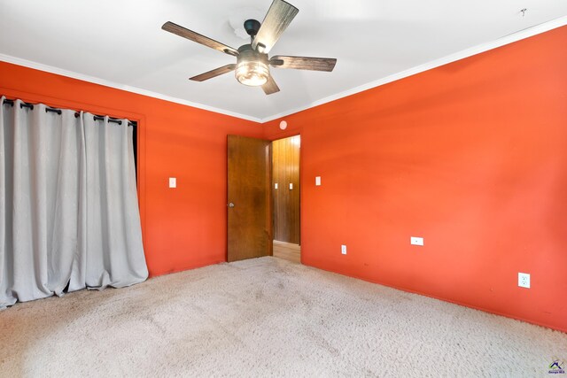 spare room with crown molding, carpet flooring, and ceiling fan