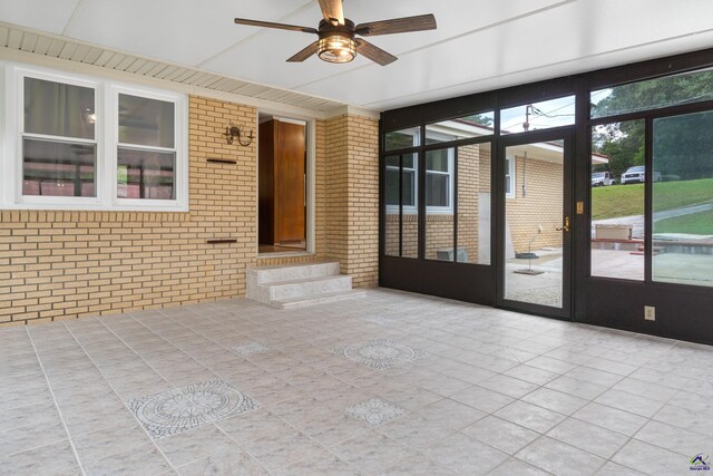 unfurnished sunroom featuring ceiling fan