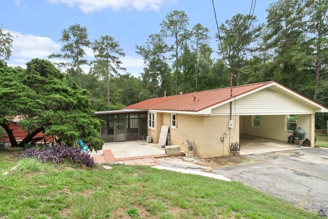 rear view of property with a sunroom and a carport