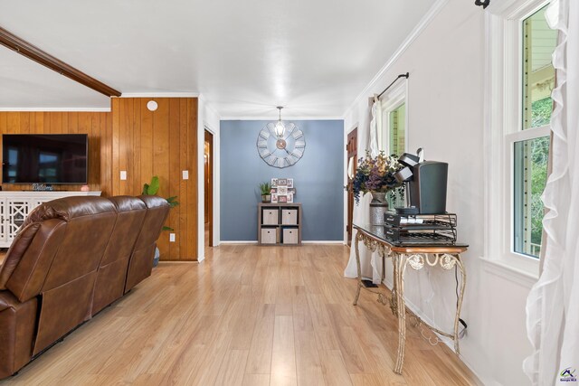 foyer featuring an inviting chandelier, light wood-type flooring, wood walls, and crown molding