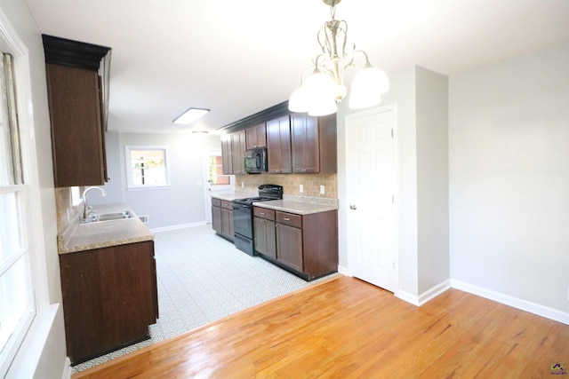 kitchen featuring black / electric stove, a sink, light wood-style flooring, decorative backsplash, and light countertops