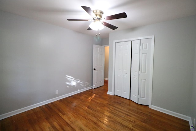 unfurnished bedroom featuring baseboards, wood finished floors, a closet, and a ceiling fan