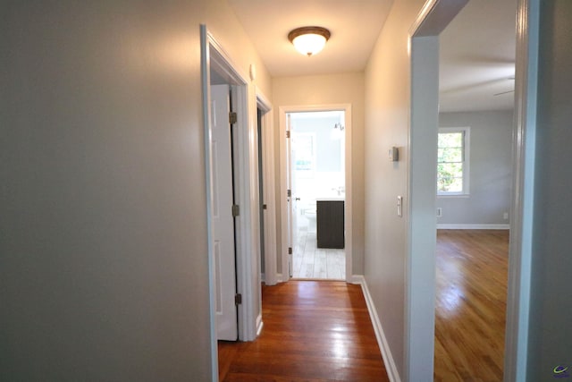 hall with dark wood-type flooring and baseboards