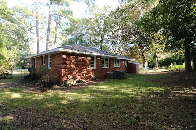 view of home's exterior featuring brick siding, a lawn, and central air condition unit