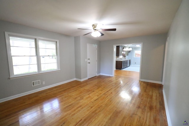 empty room with a ceiling fan, light wood-style flooring, and baseboards