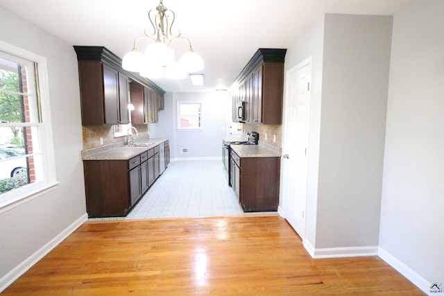 kitchen with a sink, electric range oven, a chandelier, and dark brown cabinetry
