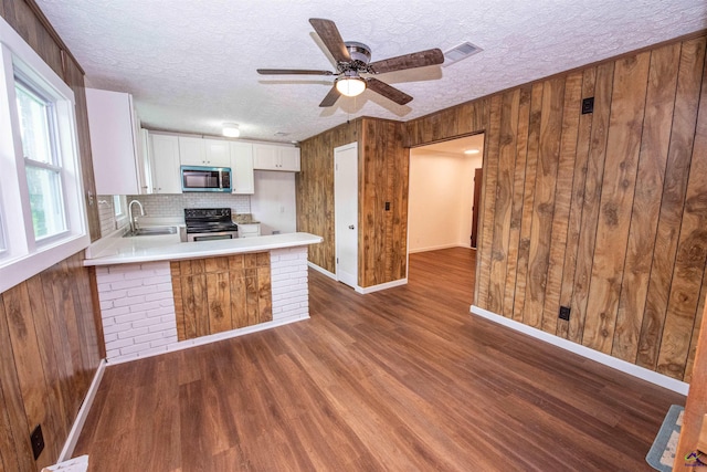 kitchen featuring appliances with stainless steel finishes, wood walls, dark hardwood / wood-style flooring, and decorative backsplash