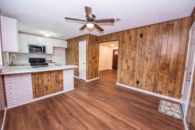 kitchen featuring black range oven, wooden walls, sink, and dark wood-type flooring