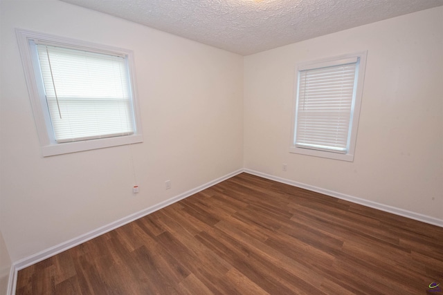 empty room with a textured ceiling and dark wood-type flooring