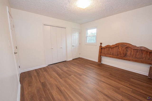 unfurnished bedroom with a textured ceiling and dark hardwood / wood-style flooring