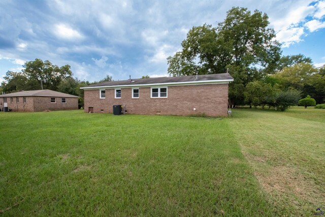 back of house with cooling unit and a lawn