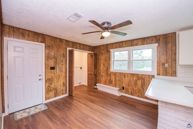 bathroom featuring wood-type flooring, a textured ceiling, wood walls, and ceiling fan