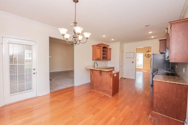 kitchen featuring hanging light fixtures, ornamental molding, light hardwood / wood-style floors, a kitchen bar, and a chandelier