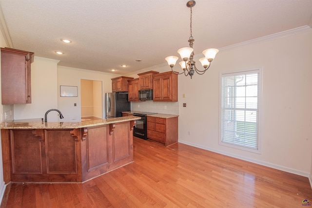 kitchen with hanging light fixtures, light hardwood / wood-style flooring, kitchen peninsula, black appliances, and ornamental molding