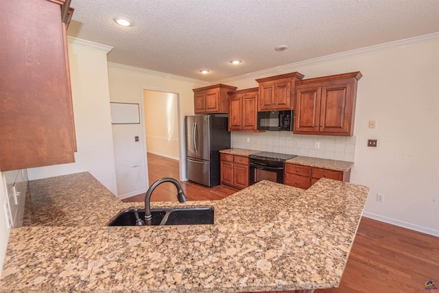 kitchen with black appliances, sink, dark hardwood / wood-style floors, light stone countertops, and kitchen peninsula