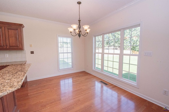 unfurnished dining area with ornamental molding, a chandelier, and wood-type flooring