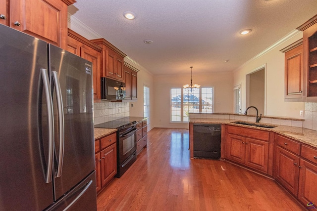 kitchen featuring sink, an inviting chandelier, wood-type flooring, a textured ceiling, and black appliances