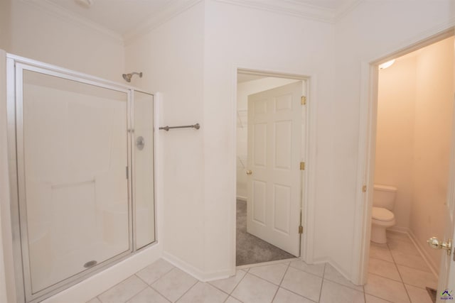 bathroom featuring tile patterned flooring, toilet, a shower with shower door, and crown molding