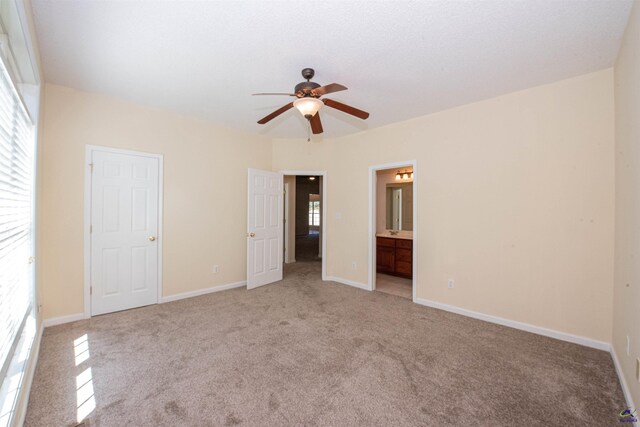 unfurnished bedroom featuring ceiling fan, light carpet, and ensuite bath