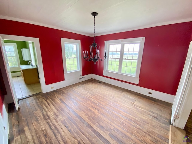 unfurnished dining area with an inviting chandelier, crown molding, dark hardwood / wood-style flooring, and sink