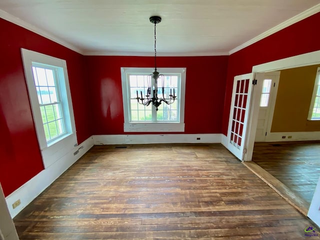 unfurnished dining area with ornamental molding, an inviting chandelier, and dark wood-type flooring