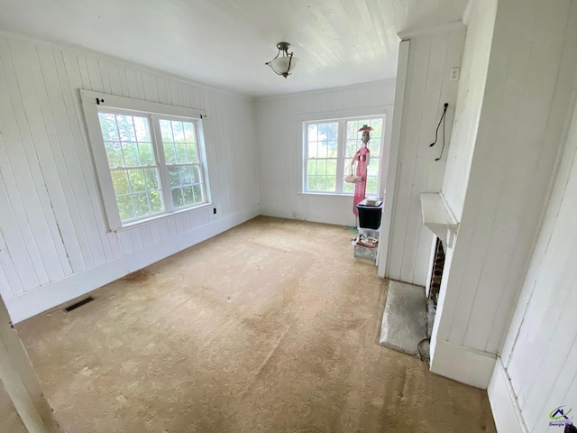 interior space with wood walls, light carpet, and a wealth of natural light