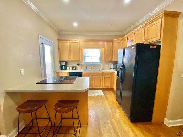 kitchen featuring black appliances, light hardwood / wood-style floors, crown molding, and light brown cabinets