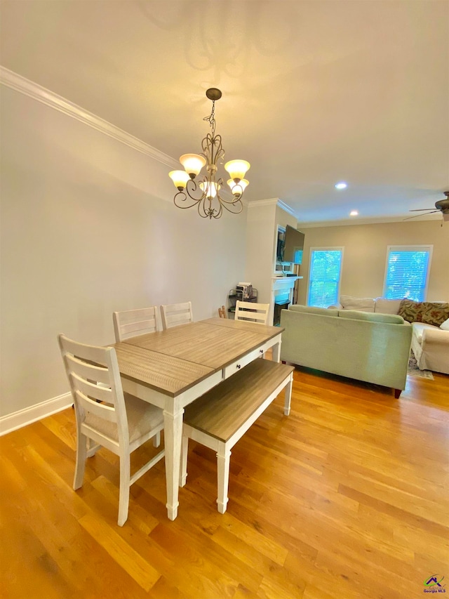 dining space with ceiling fan with notable chandelier, light hardwood / wood-style flooring, and ornamental molding