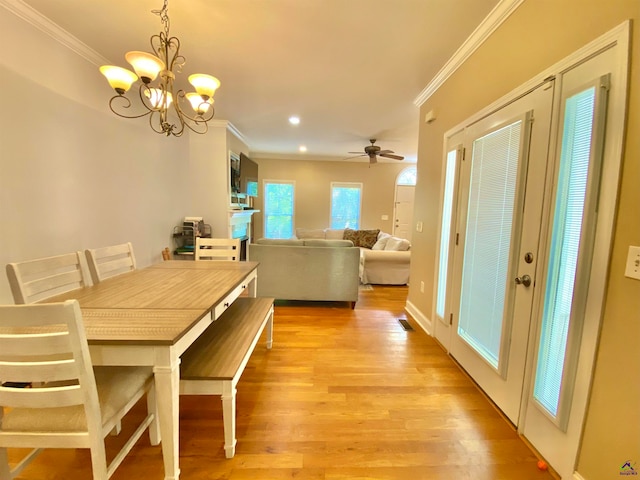 dining area with ceiling fan with notable chandelier, light wood-type flooring, and crown molding