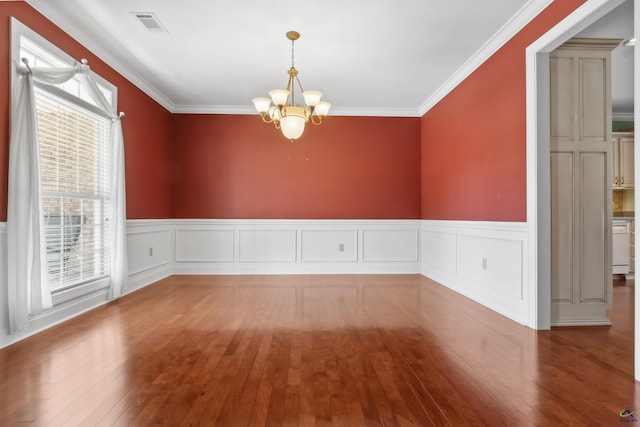 unfurnished room featuring an inviting chandelier, crown molding, hardwood / wood-style flooring, and a wealth of natural light