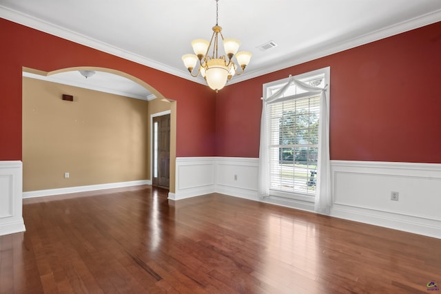 spare room featuring dark wood-type flooring, ornamental molding, and a notable chandelier