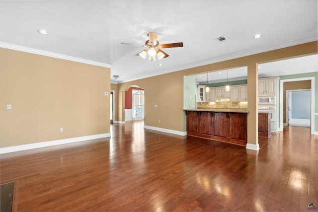 unfurnished living room with crown molding, ceiling fan, and dark wood-type flooring