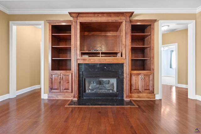 unfurnished living room featuring built in features, dark hardwood / wood-style floors, crown molding, and a high end fireplace