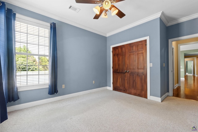 unfurnished bedroom with a closet, crown molding, carpet, and ceiling fan