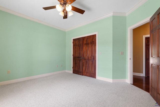 unfurnished bedroom with crown molding, ceiling fan, a closet, and carpet