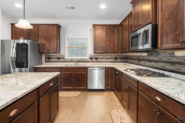 kitchen with light hardwood / wood-style flooring, decorative light fixtures, sink, light stone counters, and stainless steel appliances