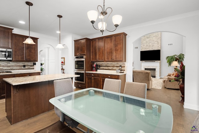 dining space featuring a fireplace, dark hardwood / wood-style floors, ornamental molding, and a chandelier