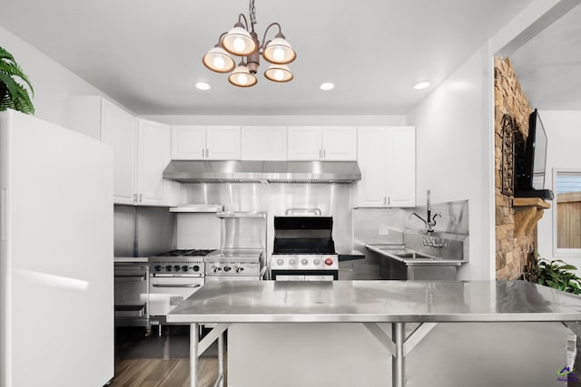 kitchen with white cabinets, decorative light fixtures, wall chimney exhaust hood, stainless steel counters, and white fridge