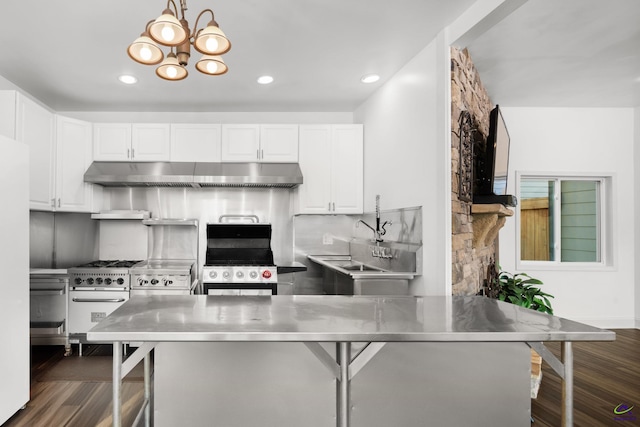 kitchen with white cabinets, black range, dark wood-type flooring, stainless steel counters, and a breakfast bar