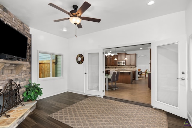 interior space with ceiling fan with notable chandelier and dark hardwood / wood-style floors