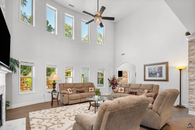 living room featuring a fireplace, hardwood / wood-style flooring, a towering ceiling, and a healthy amount of sunlight