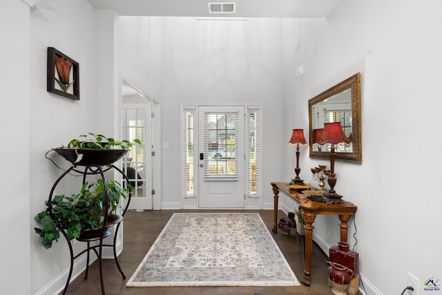 entryway with dark wood-type flooring and a towering ceiling