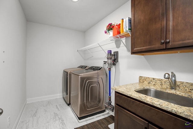 laundry room featuring washing machine and clothes dryer, cabinets, and sink