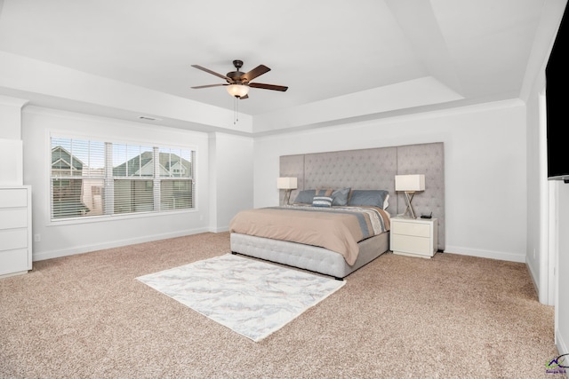 carpeted bedroom featuring ceiling fan and a tray ceiling