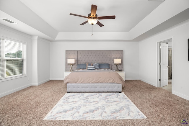 carpeted bedroom featuring ceiling fan, a tray ceiling, and connected bathroom