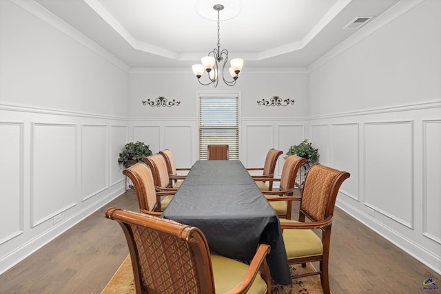 dining space with dark hardwood / wood-style floors, a tray ceiling, an inviting chandelier, and ornamental molding