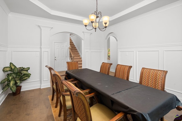 dining room featuring ornamental molding, decorative columns, a chandelier, and dark hardwood / wood-style flooring